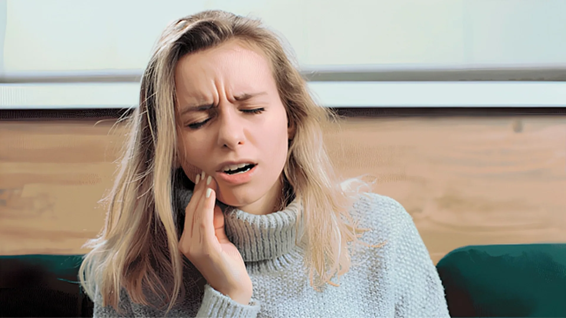 Person holding their cheek in discomfort
